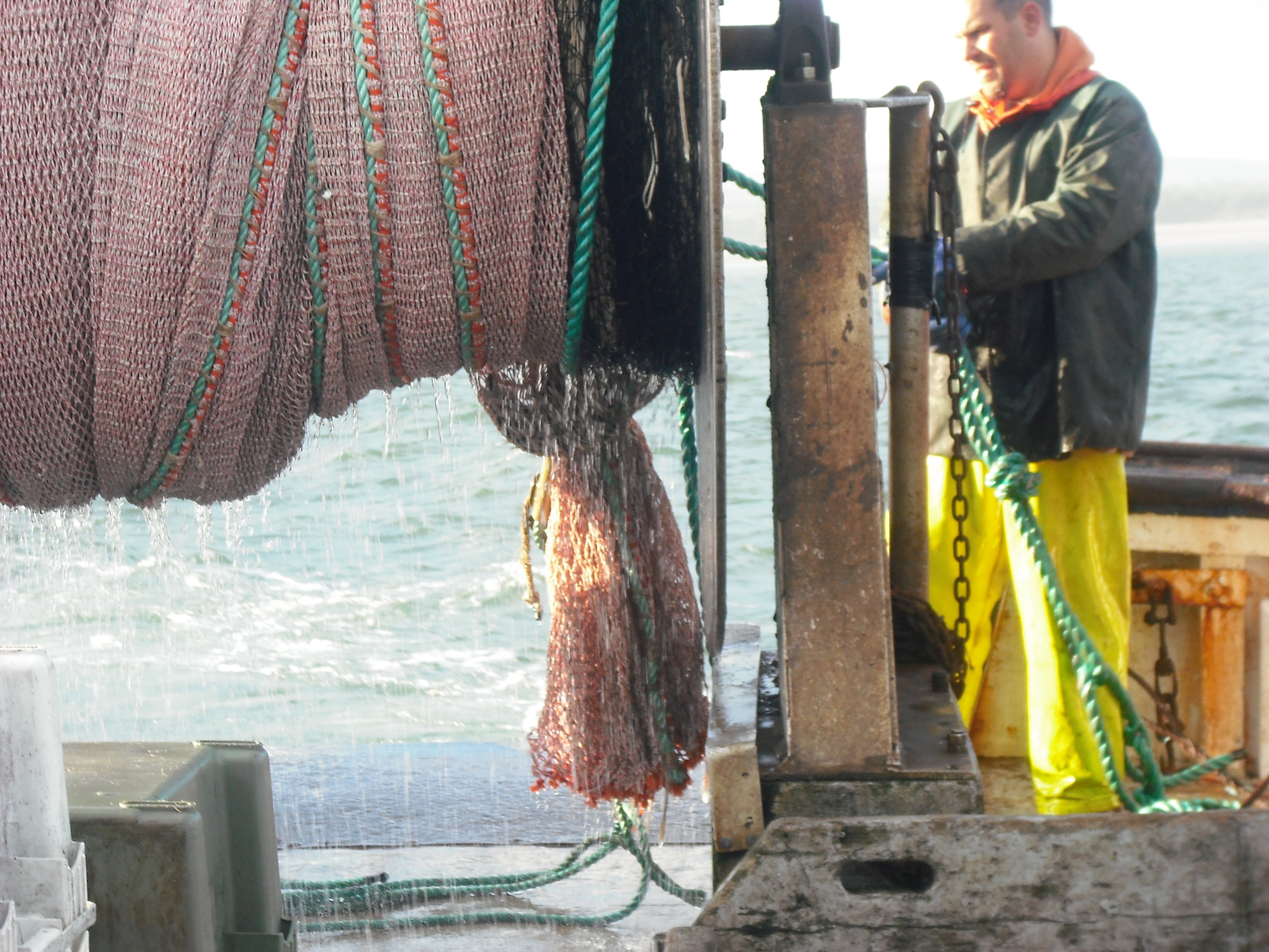 Stern of boat with trawl net on reel and fisherman